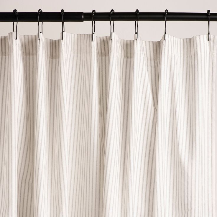 a white curtain hanging on a black rod with pinstripe pattern in the background