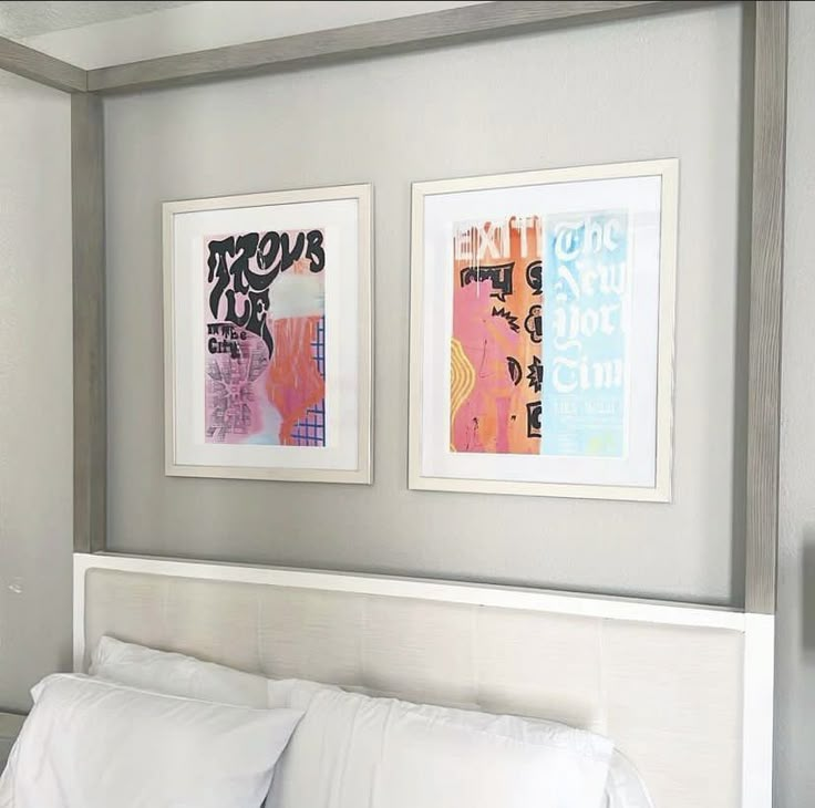 two framed pictures on the wall above a bed