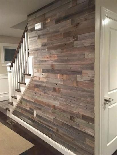 a wooden wall next to a white door in a room with hardwood floors and stairs