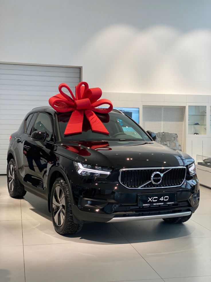 a black car with a red bow on it's hood in a showroom