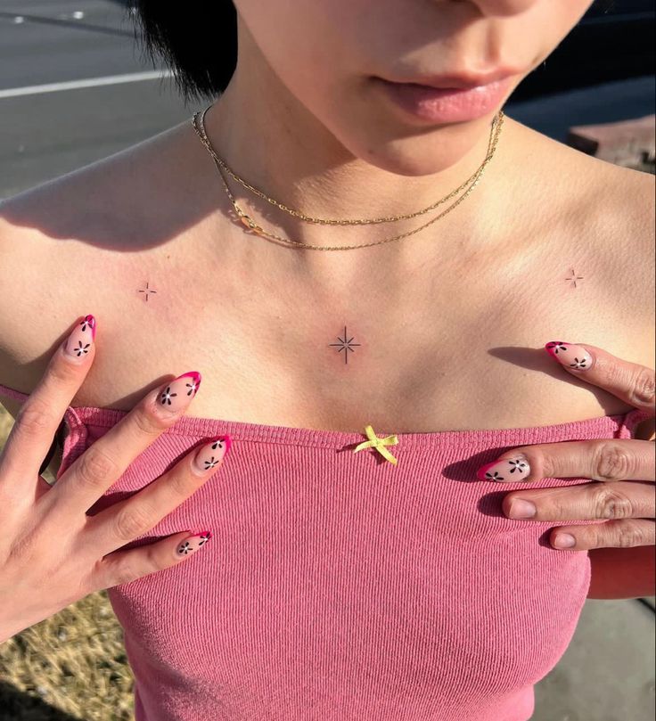 a woman with pink and yellow nails holding her hand up to her chest while wearing a pink top