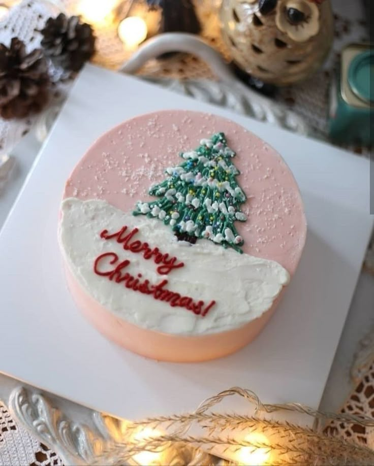 a decorated christmas cake sitting on top of a white table next to a lit candle