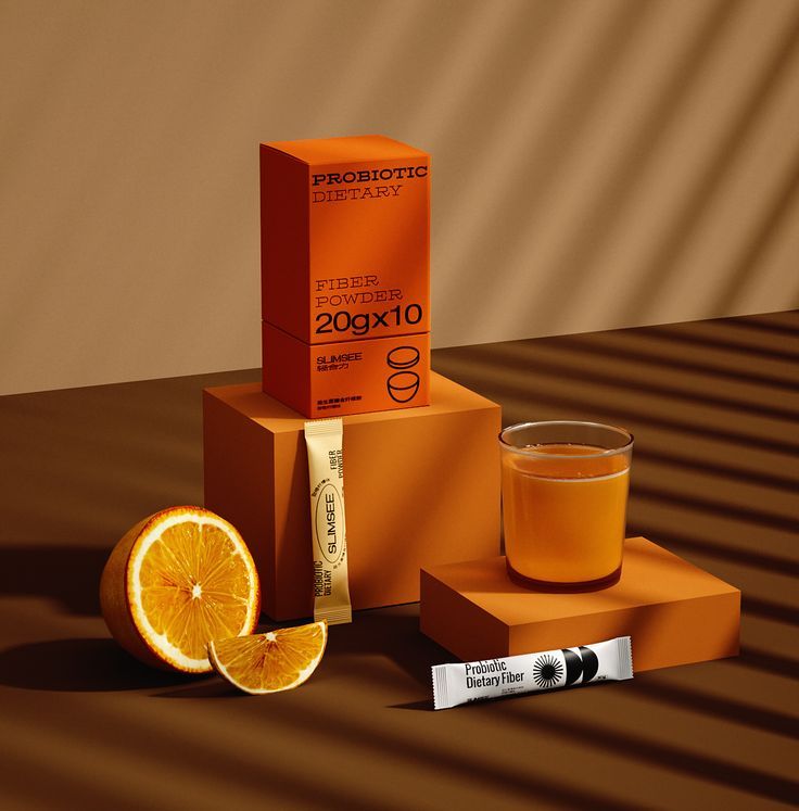 an orange sitting on top of a box next to a glass of liquid and some slices of fruit