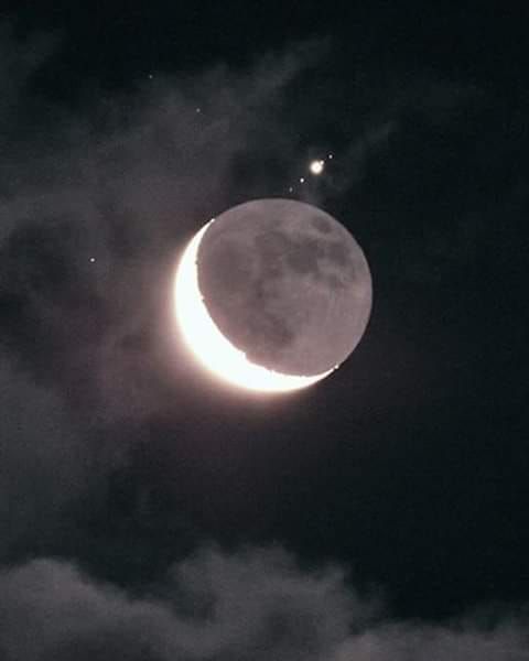 the moon is in the sky with clouds around it and an image of two stars