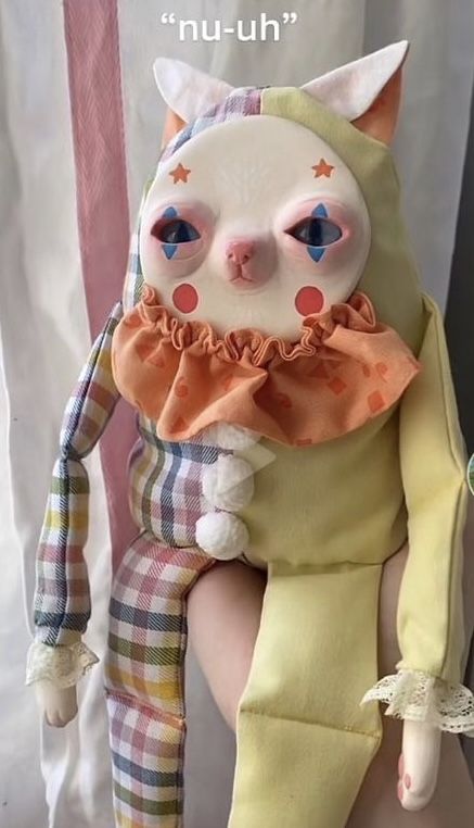 a white cat with blue eyes sitting on top of a stuffed animal doll next to a curtain