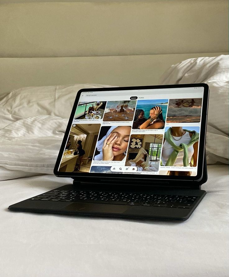 an open laptop computer sitting on top of a bed next to a white comforter