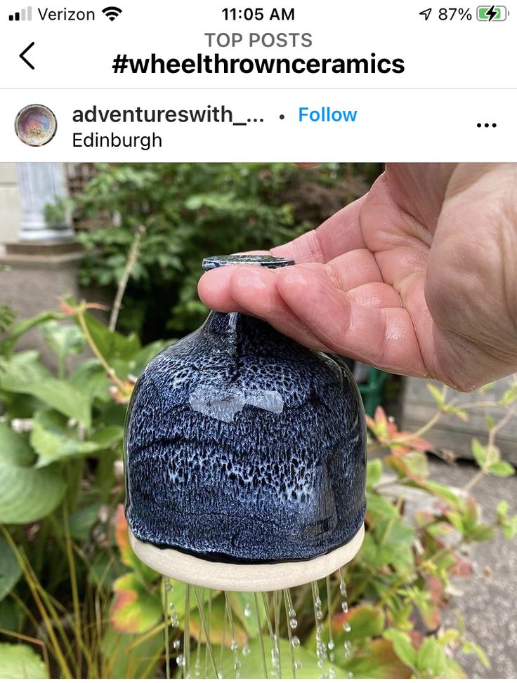 someone is holding their hand over the top of a blue vase with water coming out of it