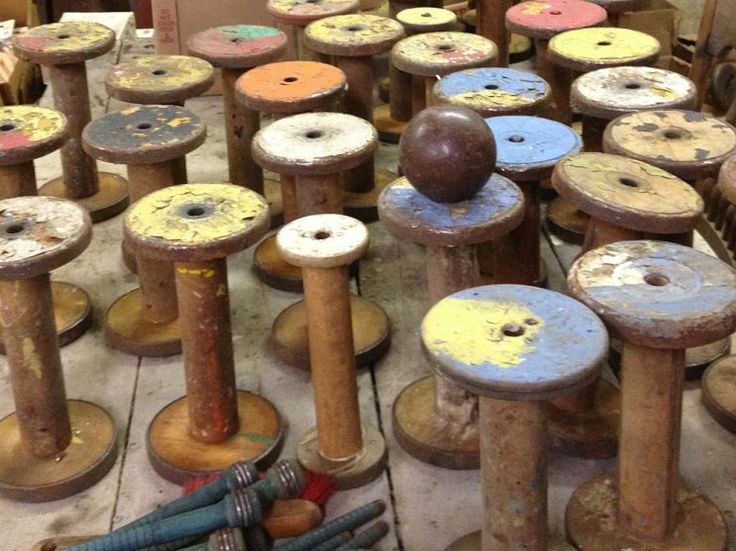 many spools of thread sitting on top of wooden poles in a room filled with other spools