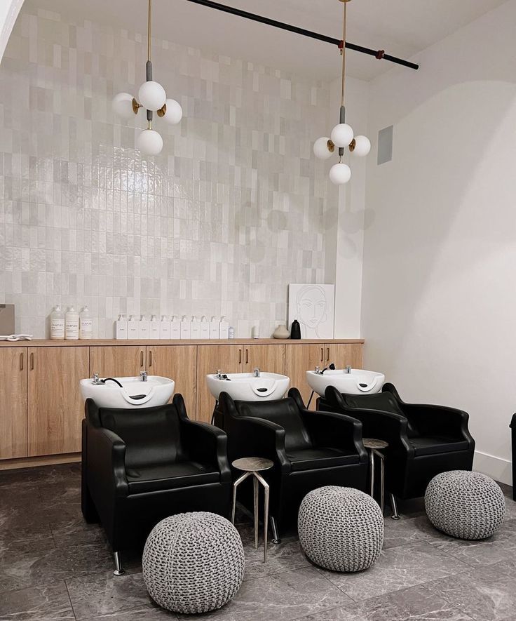 three chairs and two stools in a room with lights hanging from the ceiling above them