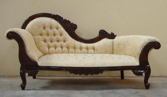 an antique style couch sitting on top of a cement floor in front of a wall