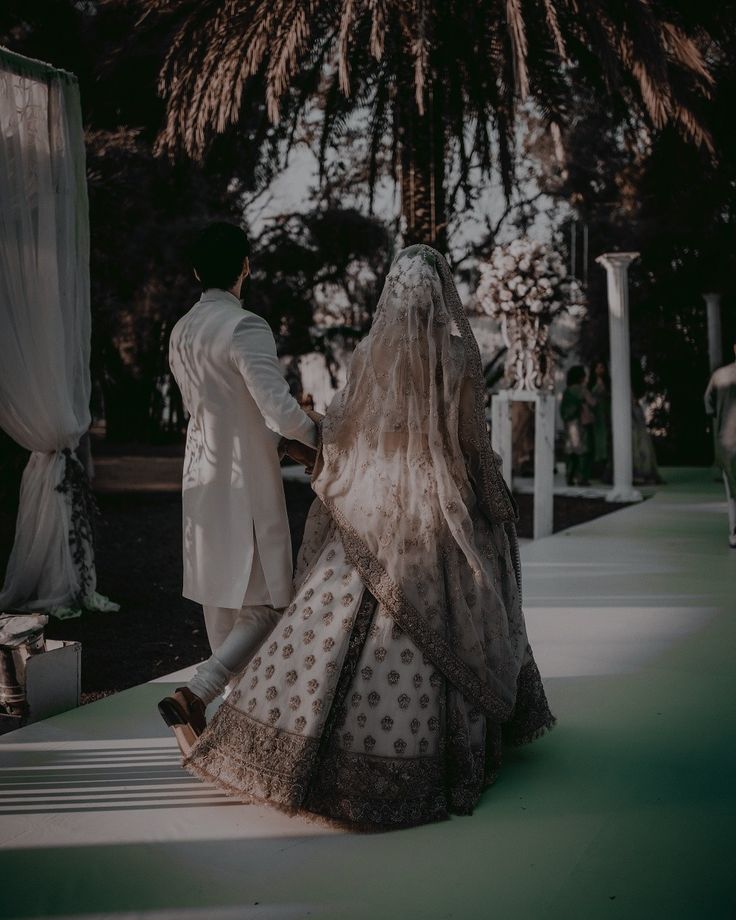 a bride and groom walking down the aisle at their wedding ceremony in front of a palm tree