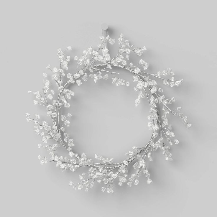 a wreath with white flowers and leaves on a gray background