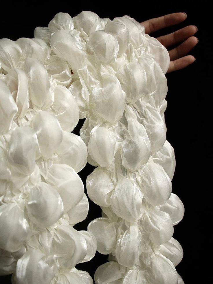 a hand is reaching up to a bunch of white flowers on a black background,