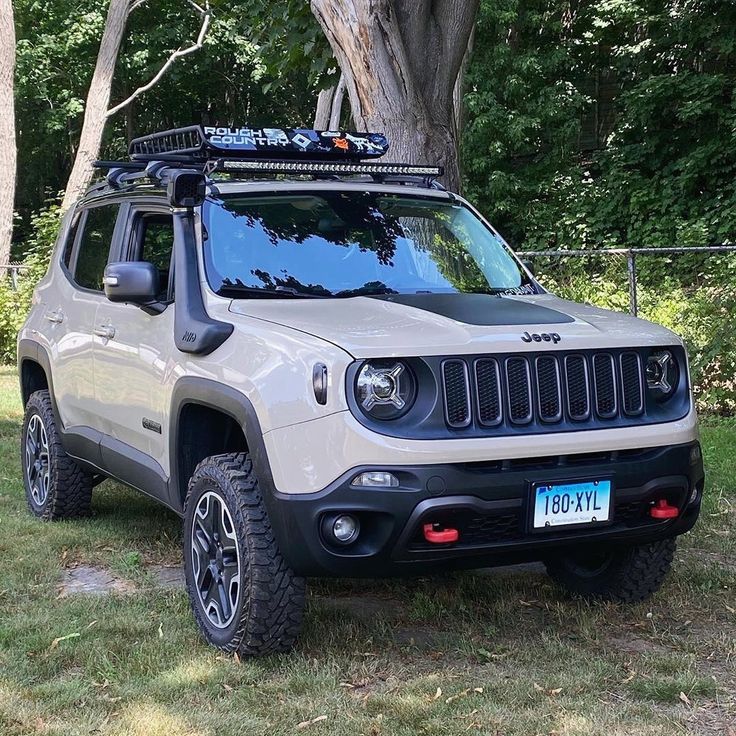 a white jeep parked in the grass next to a tree