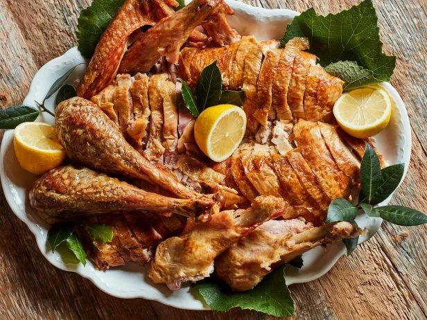 a white plate topped with sliced chicken and lemons on top of a wooden table