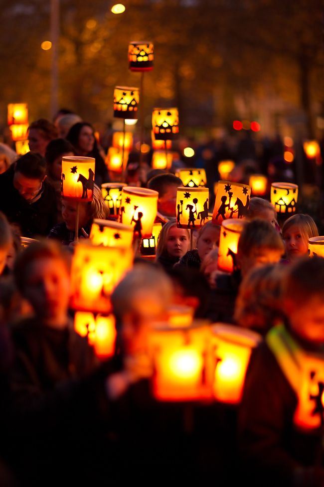 many people are holding lit candles in the shape of faces and heads as they look at them