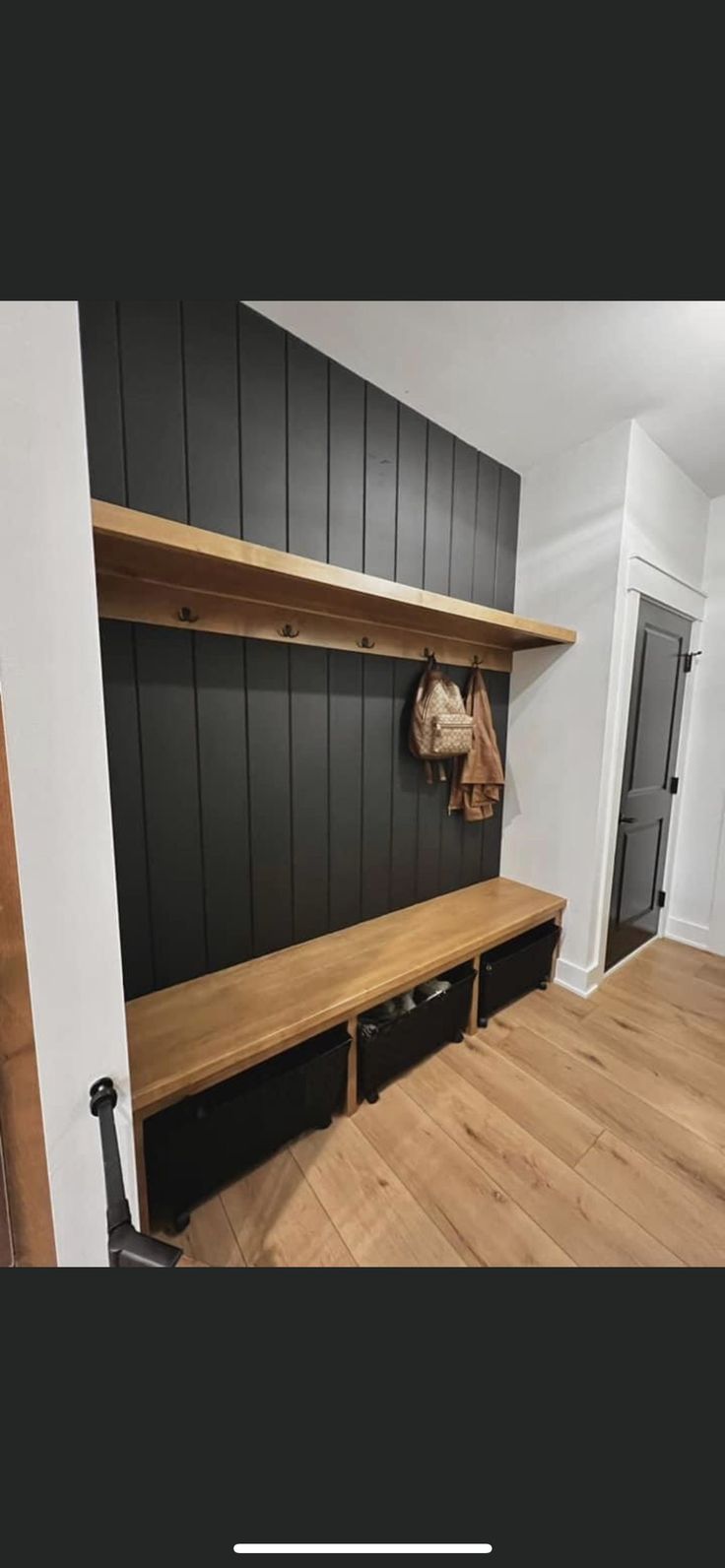 there is a bench in the corner of this room with black walls and wood flooring