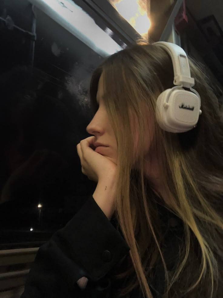 a woman with headphones on looking out the window