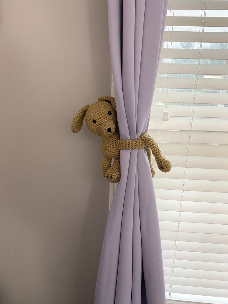 a stuffed dog is peeking out from behind the curtains