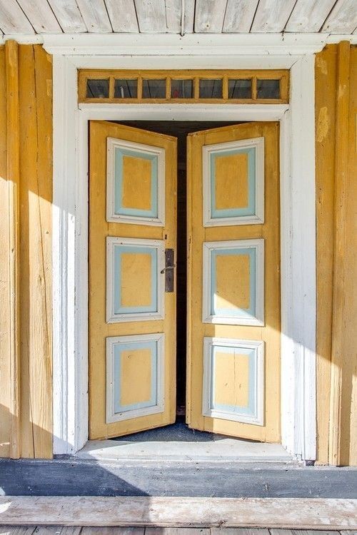 an open yellow door on the side of a building with wood slats around it