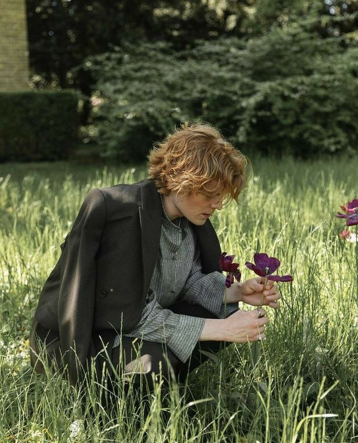 a person kneeling in the grass with flowers