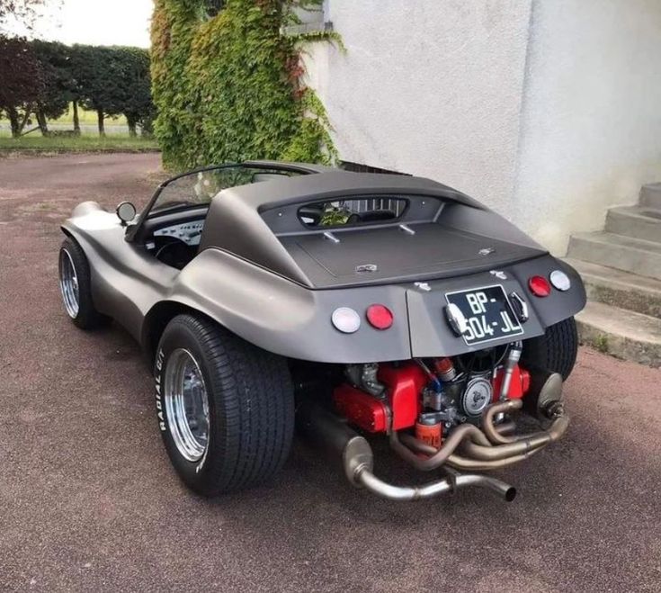 a silver sports car parked in front of a building with its hood up and engine out