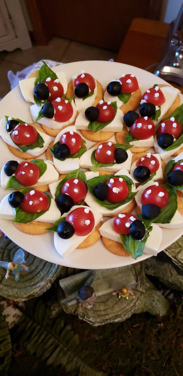 a white plate topped with cookies covered in ladybugs and cherries on top of leafy greens