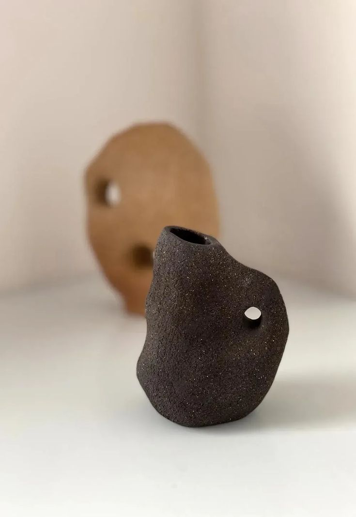 two small objects sitting on top of a white table next to each other, one with a hole in the middle