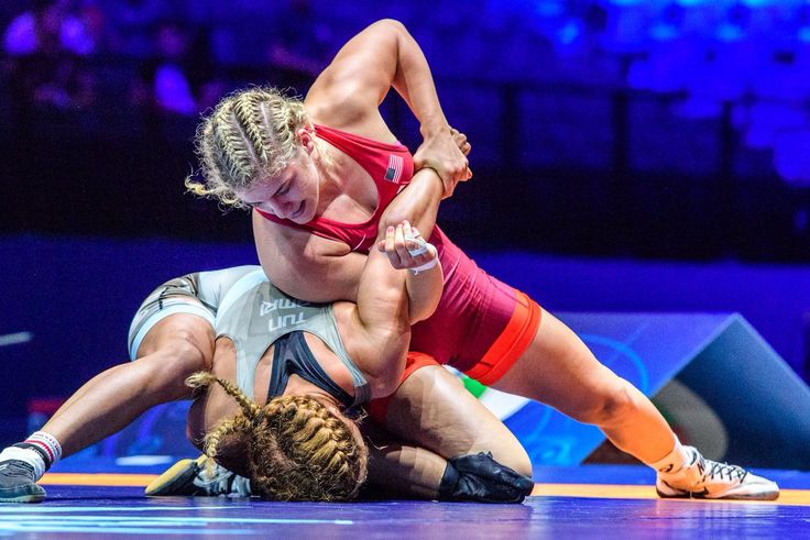 two women wrestling in an arena during a match, one is holding the other's leg