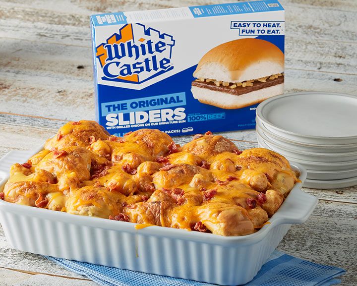 a casserole dish filled with meat and cheese next to a carton of white castle sliders