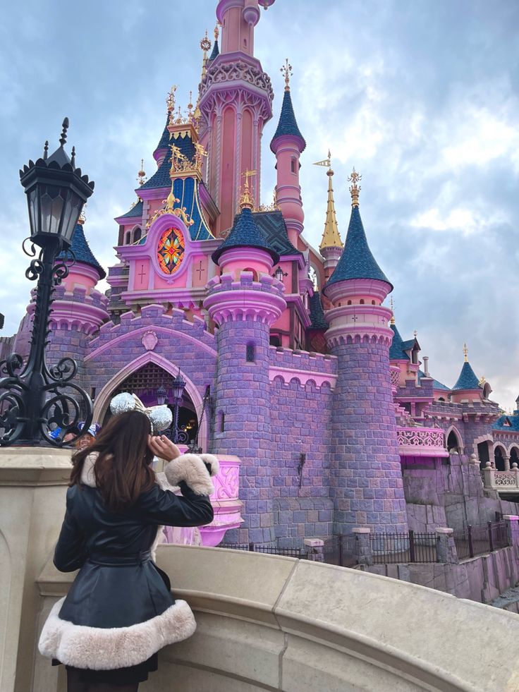 a woman standing in front of a castle with a stuffed animal next to her face