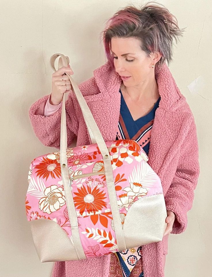 a woman is holding a pink floral bag