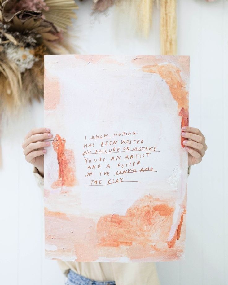 a person holding up a piece of paper with writing on it and flowers in the background