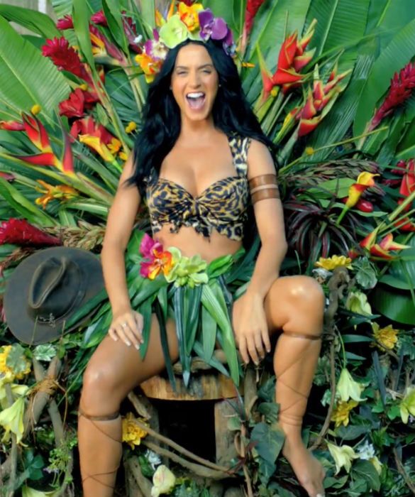 a statue of a woman sitting on top of a tree stump surrounded by tropical plants