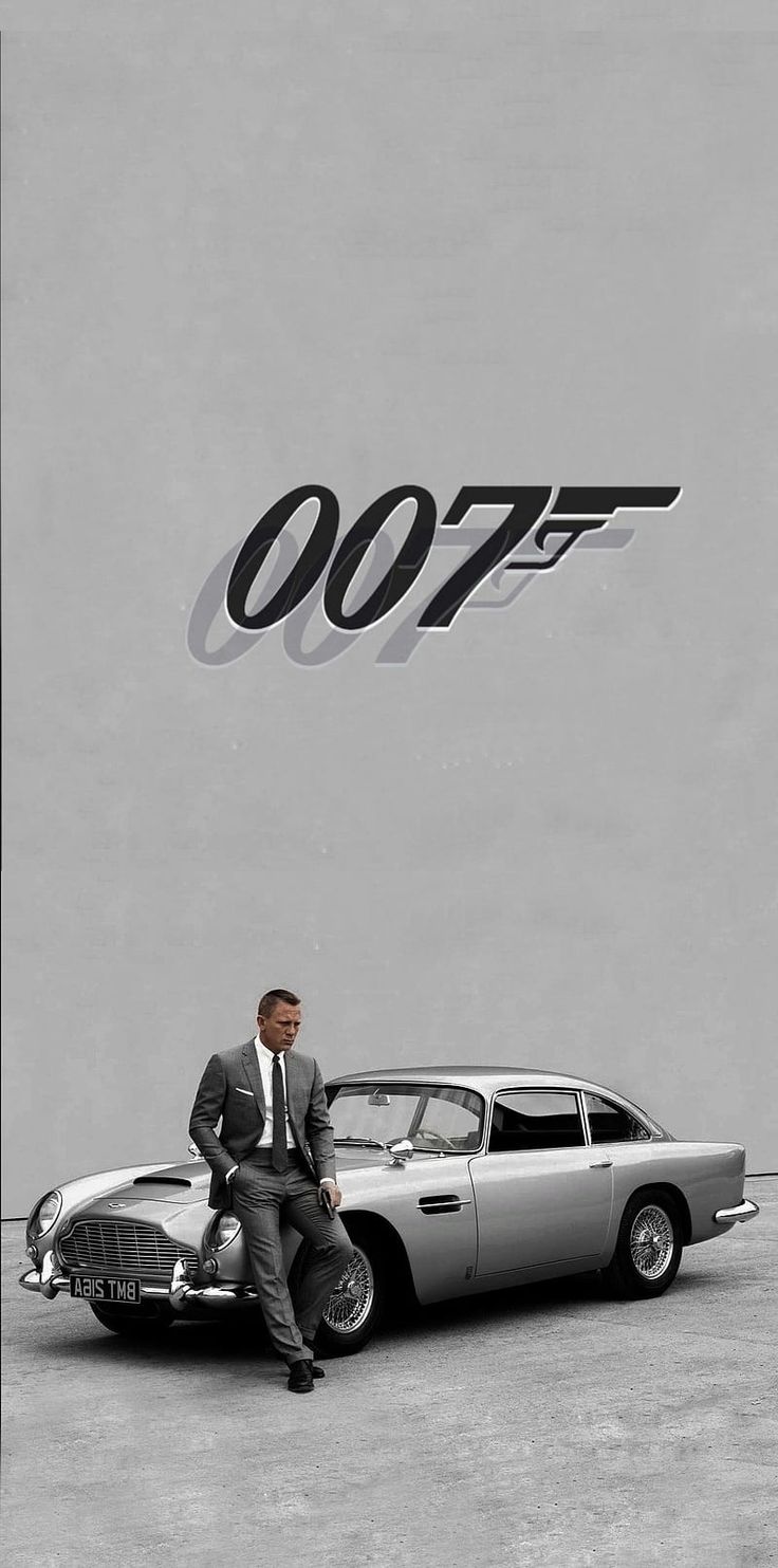 a man sitting on top of a car next to a james bond movie poster that reads 007