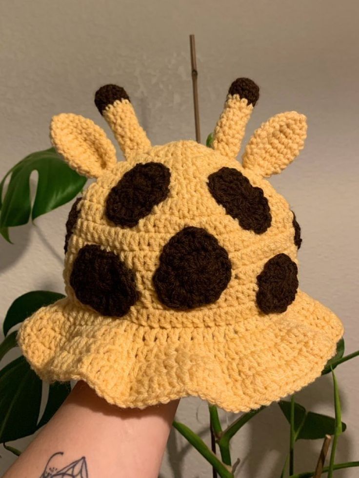 a crocheted giraffe hat on someone's arm