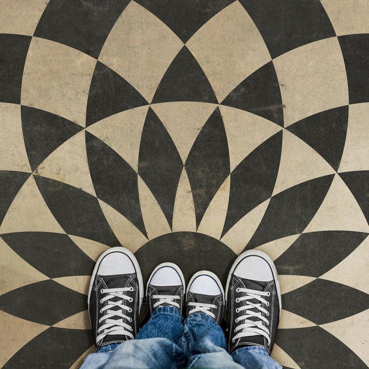 a person standing in front of a black and white tile floor with their feet up