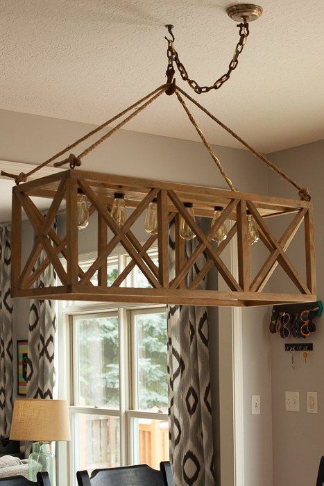 a chandelier hanging from the ceiling in a dining room with chairs and table