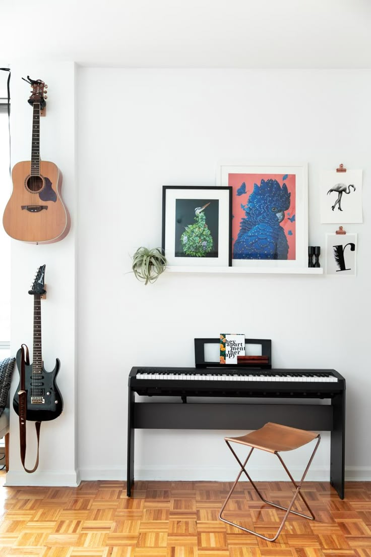 there is a black piano in the room with guitars on the wall and pictures above it