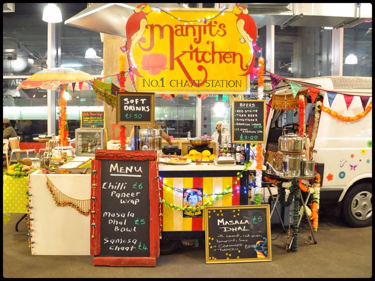 a food stand with lots of signs and decorations on it's sides, including an umbrella