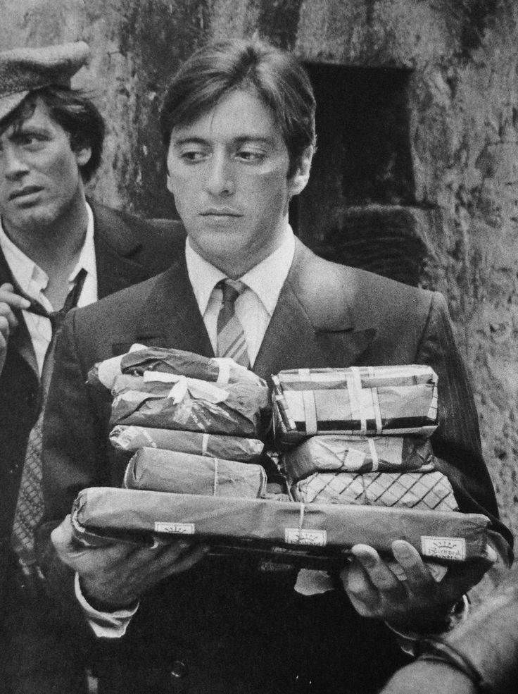 black and white photograph of two men carrying food in front of him, one holding a sandwich