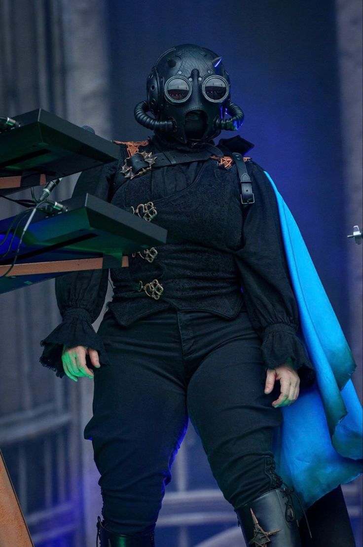 a woman dressed in black and wearing a gas mask