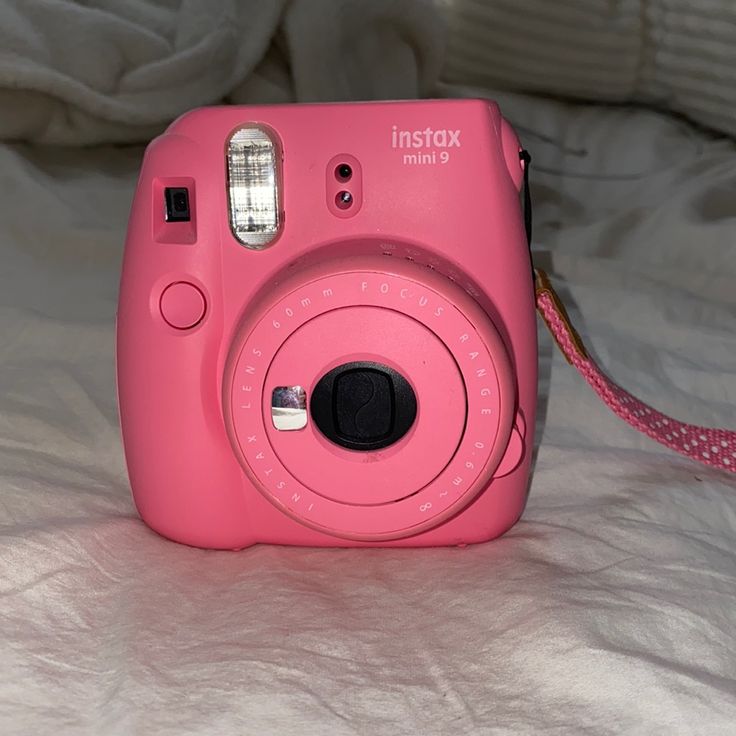 a pink camera sitting on top of a bed