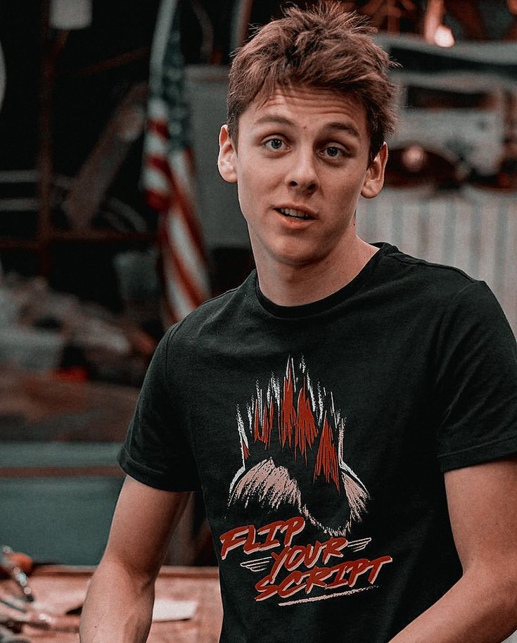 a young man standing in front of a table with food on it and looking at the camera