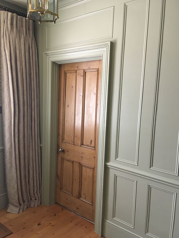 an empty room with wood floors and white walls, has a wooden door in the corner