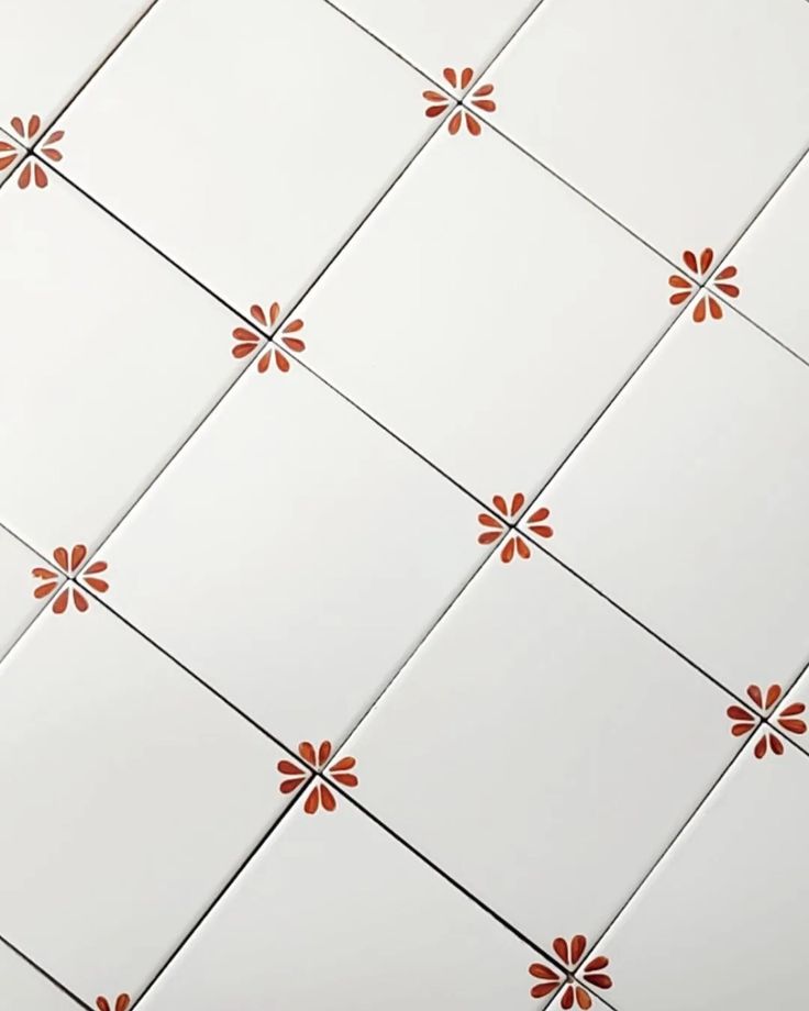 an orange and white tile pattern with flowers on the bottom half of each tile wall