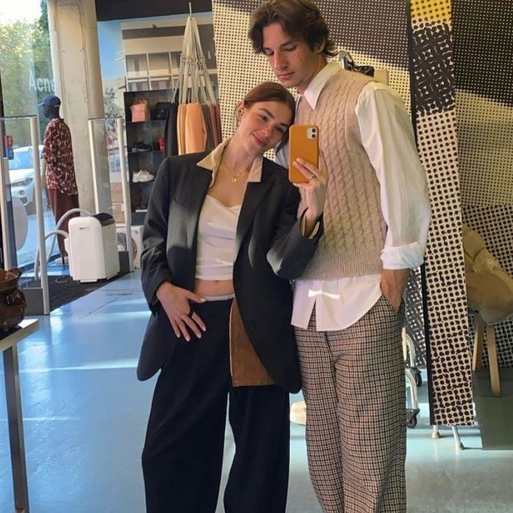 a man and woman standing next to each other in front of a store display window