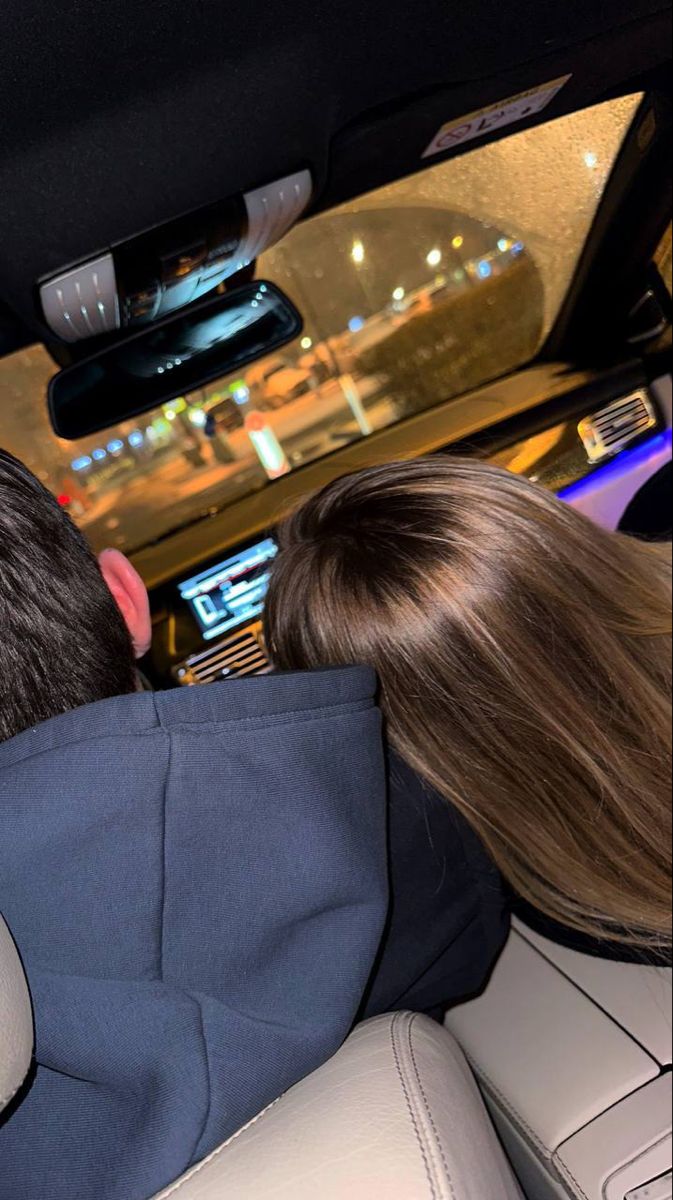 two people sitting in the back seat of a car looking at something on the screen