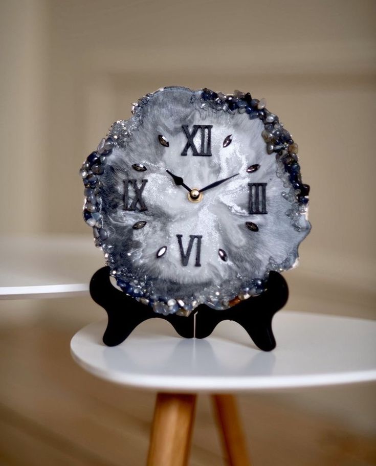 a clock with roman numerals on it sitting on top of a white table