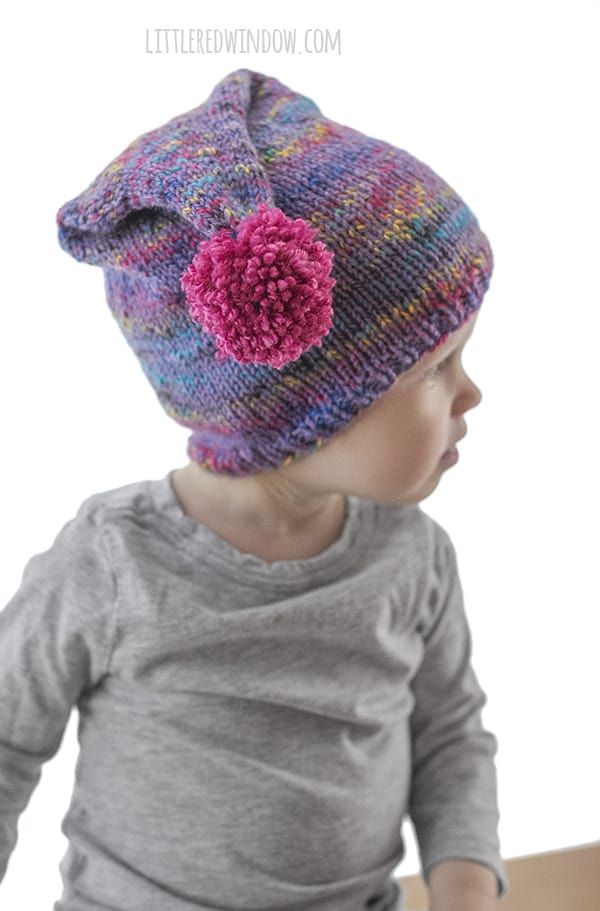 a small child wearing a knitted hat with a flower on the front and side